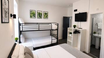 A bunk bed room with a desk, TV, and a bathroom with a mirror and sink.