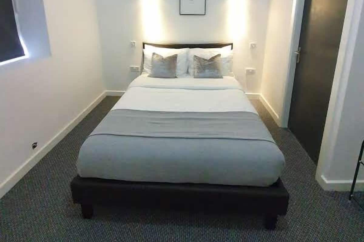 A bedroom with a bed, a framed picture on the wall, and a door.