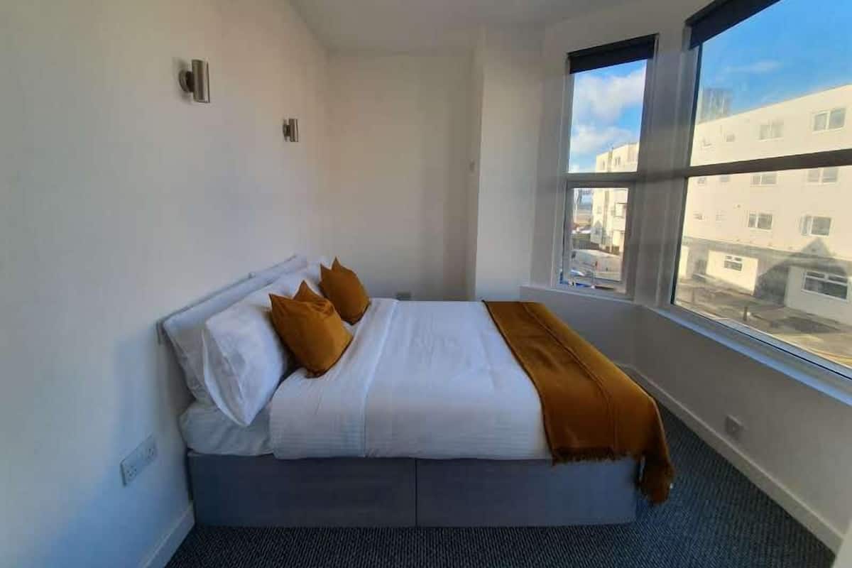 A hotel room with a bed, a window, and a view of buildings outside.