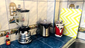 A kitchen with a blender, a kettle, and a red appliance on a blue-tiled countertop. - Departamento Alice (Cusco)