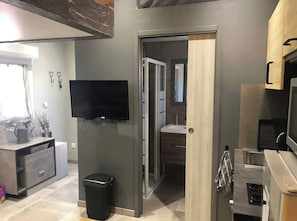 A modern kitchen with a built-in oven, a trash bin, and a wooden cabinet. - Charming, fully furnished studio in Martigues (Martigues)