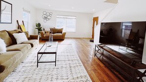 Un salon avec un canapé, une table basse, un téléviseur et un plancher en bois.