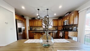 Une cuisine moderne avec des meubles en bois, des appareils en acier inoxydable et un îlot central agrémenté d’un vase en verre.