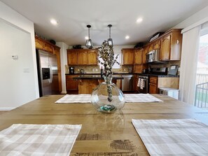 A modern kitchen with wooden cabinets, stainless steel appliances, and a central island with a glass vase.