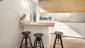 A modern kitchen with wooden cabinets, a white countertop, and three bar stools. - Apartment 293 - Clifden - sleeps 4 guests  in 2 bedrooms (Clifden)