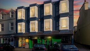 A multi-story building with large windows, a green storefront, and parked cars. - Apartment 293 - Clifden - sleeps 4 guests  in 2 bedrooms (Clifden)