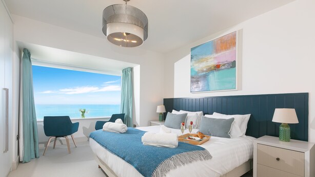 Et moderne hotelværelse med en stor seng, et skrivebord og havudsigt.