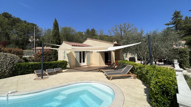 Ett poolområde med en liten byggnad, solstolar och en klarblå pool.