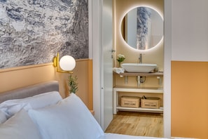 A modern hotel room with a bed, a round mirror with a light, a white sink, and storage boxes labeled "SWEET HOME". - IzzHome Corso76 (Cagliari)