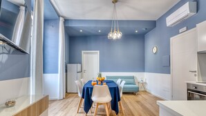 A modern dining area with a blue tablecloth, white chairs, and a chandelier. - IzzHome Corso76 (Cagliari)