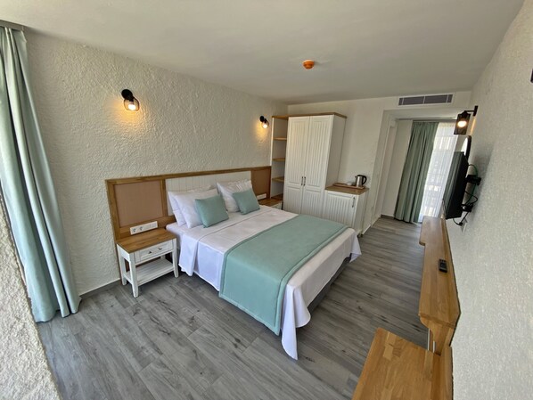 Une chambre à coucher comprenant un lit, des tables de chevet, une armoire, un téléviseur et une petite table.