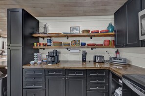 A kitchen with black cabinets, wooden countertops, and various kitchen appliances.