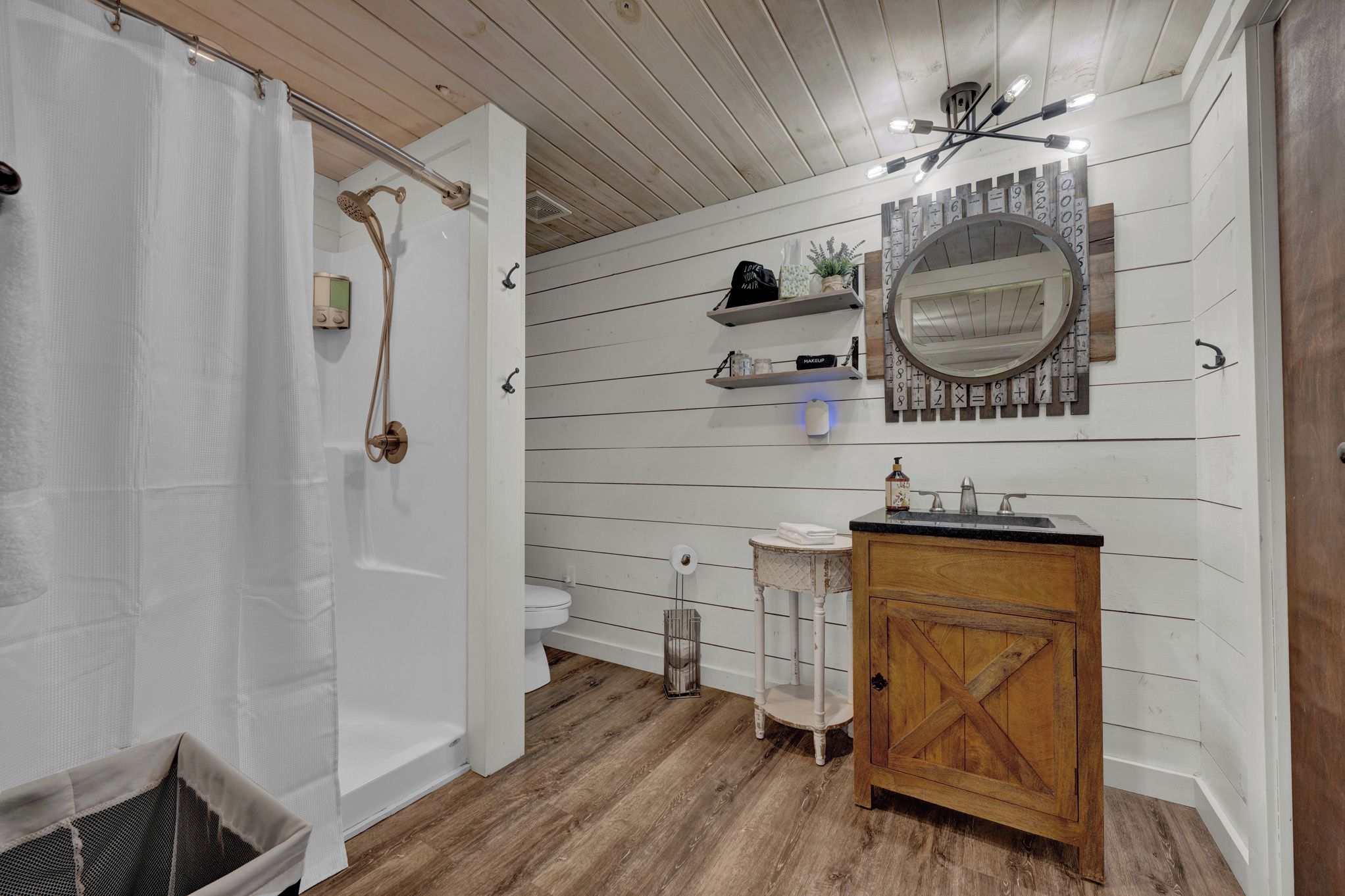 Een badkamer met een douche, toilet en een wastafel met spiegel.