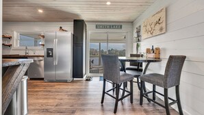 A modern kitchen with a stainless steel refrigerator, wooden flooring, and a view of Smith Lake. - Allie’s on the Rocks Pet-Friendly Lakefront Bungalow (Cullman)