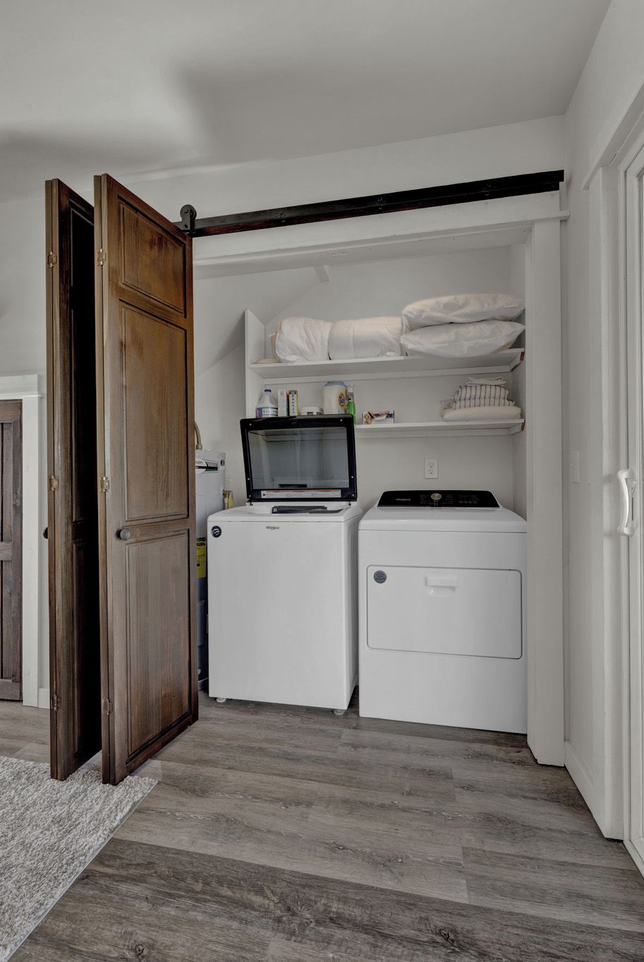 A laundry room with a washing machine, dryer, and shelves with folded linens.