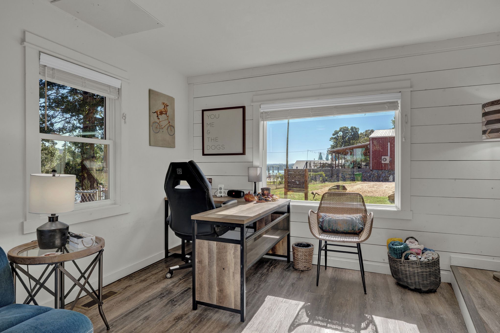 Quarto com escrivaninha, cadeira e vista para o exterior.