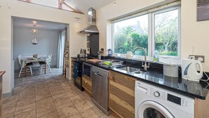 Una cucina moderna con lavastoviglie, lavatrice e un'ampia finestra vista su spazi verdi.