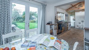 Un'ampia cucina con zona pranzo, grandi finestre e vista sul giardino.