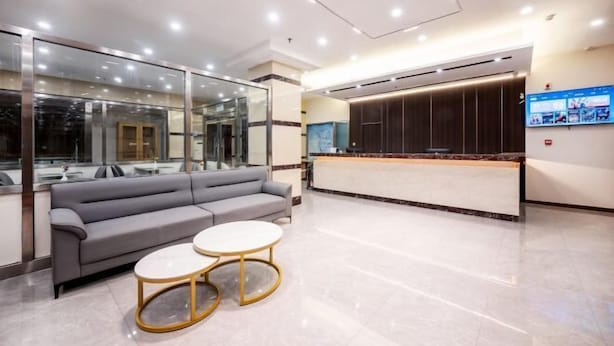 A modern reception area with a sofa, two round tables, a reception desk, and a large window. - Paibai Yun Hotel (Dalian Xianglujiao Light Rail Station Branch) (Dalian)