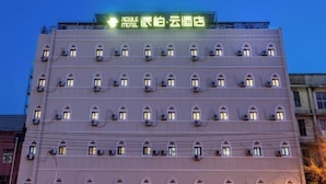 A multi-story hotel with a row of uniformly designed windows and a neon sign above the entrance. - Paibai Yun Hotel (Dalian Xianglujiao Light Rail Station Branch) (Dalian)