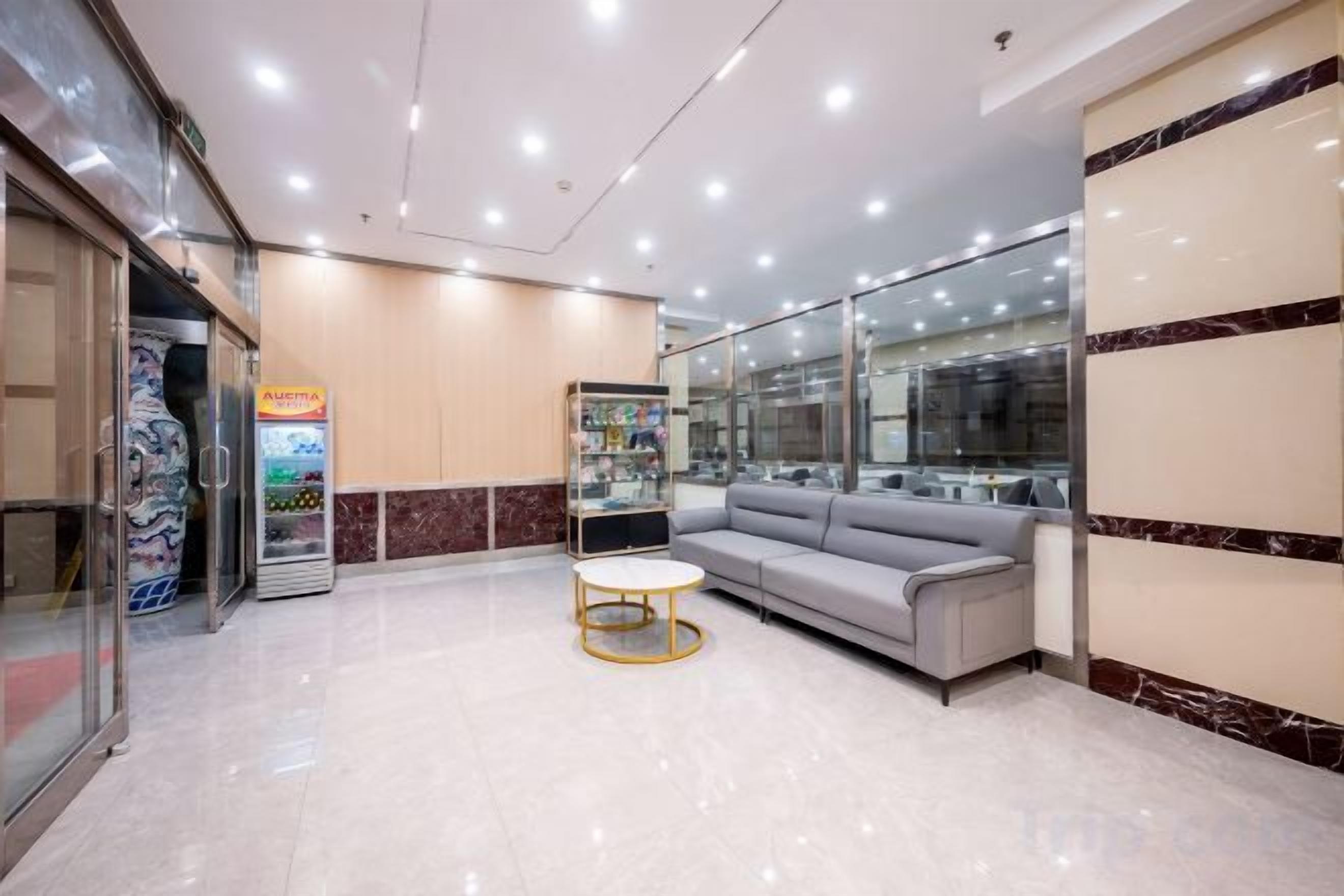A hotel lobby with a reception desk, a seating area, and a glass storefront.