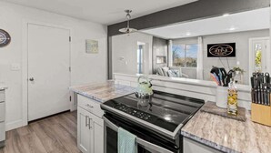 A modern kitchen with a black stove, white cabinets, and a marble countertop.