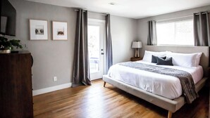 A bedroom with a bed, a nightstand, a lamp, a dresser, and two framed pictures on the wall.