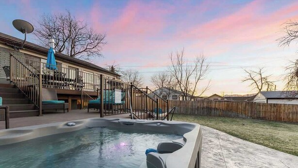 A backyard with a hot tub, outdoor seating, and a staircase leading to a deck.