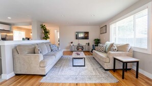 A modern living room with two sofas, a coffee table, and a TV. - Outdoor Oasis: Unwind in the hot tub under twinkling lights in your private retreat! (Arvada)