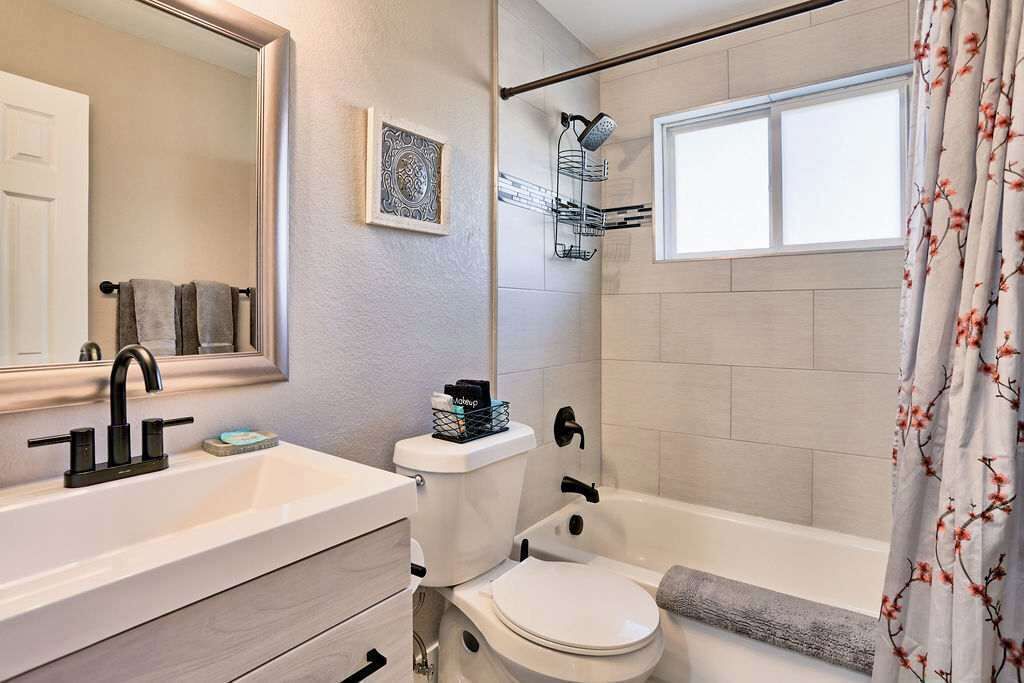 A bathroom with a white sink, a toilet, and a bathtub. There is a shower curtain with a floral pattern.