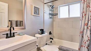 A bathroom with a white sink, a toilet, and a bathtub. There is a shower curtain with a floral pattern.