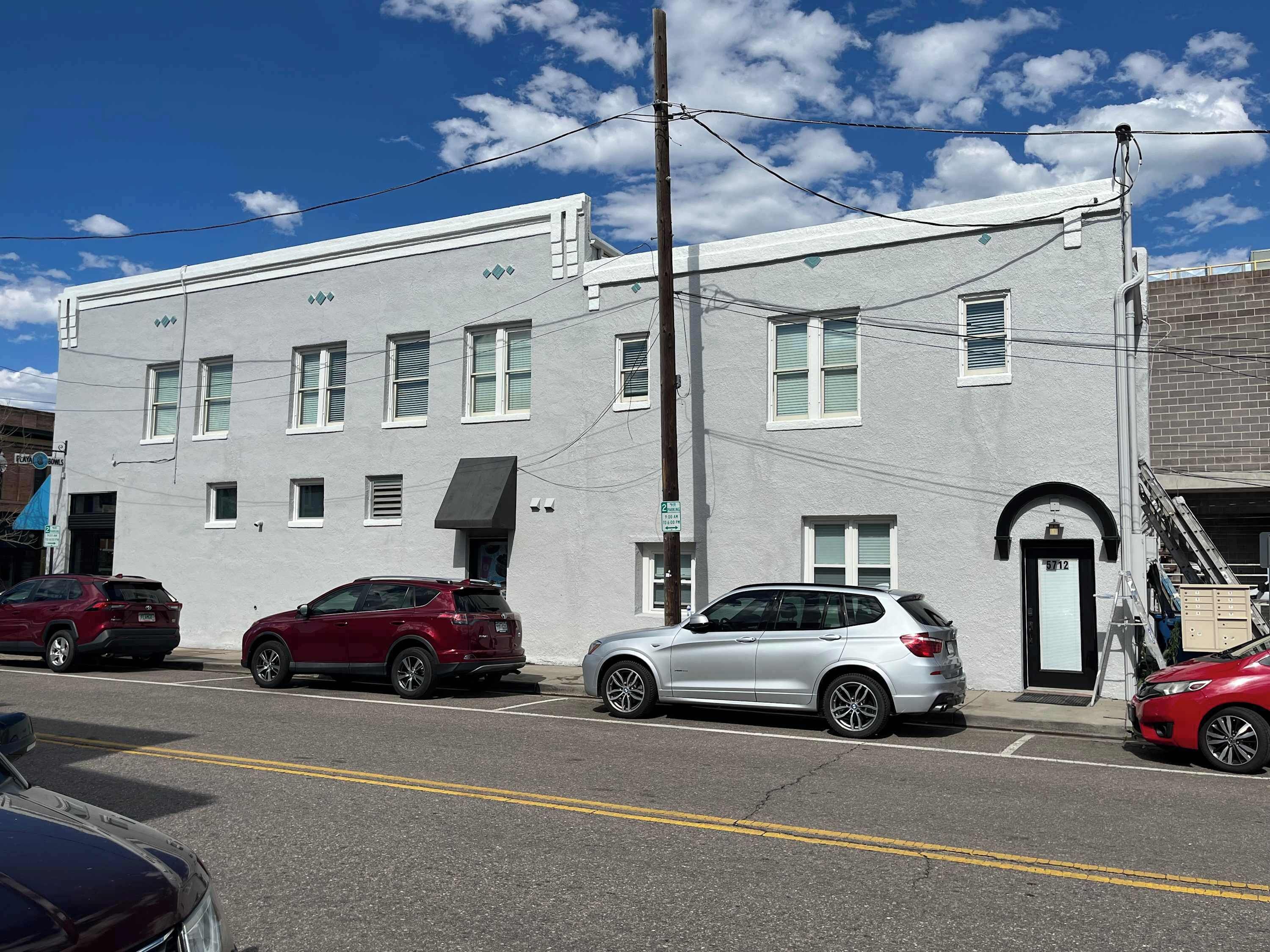 A two-story building with a flat facade, multiple windows, and a visible door.