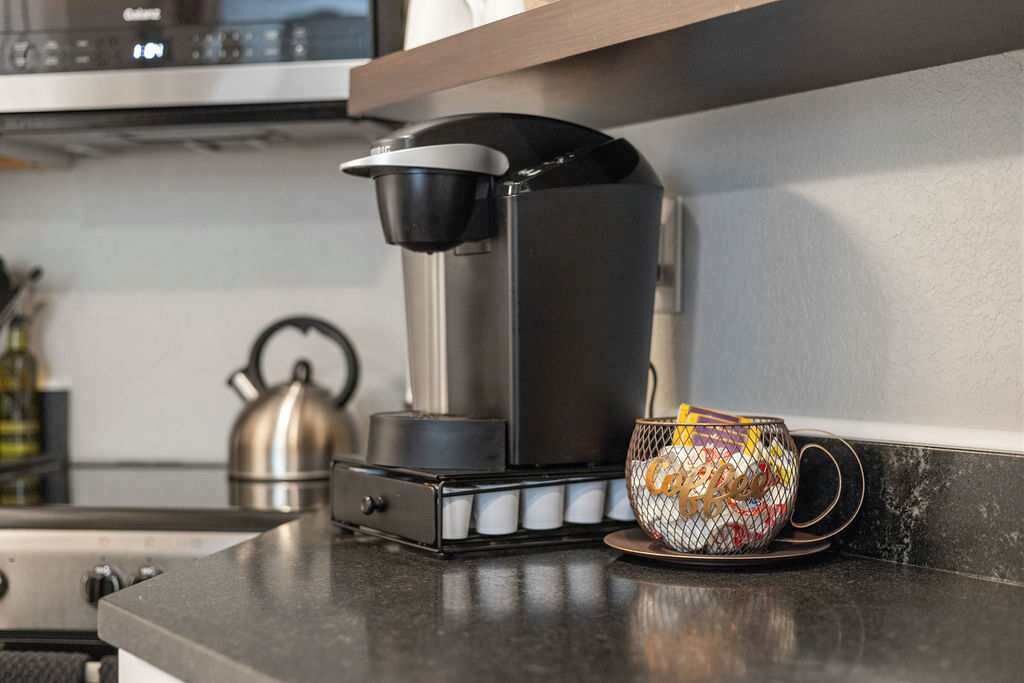Une cuisine équipée d  ’une machine à café, d’une bouilloire et d’une tasse posée sur le comptoir.