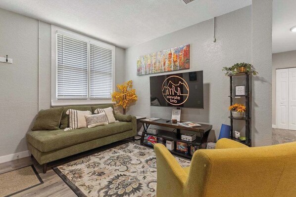 A living room with a green sofa, yellow armchair, and a TV on the wall. - Family friendly in Downtown Littleton (Littleton)