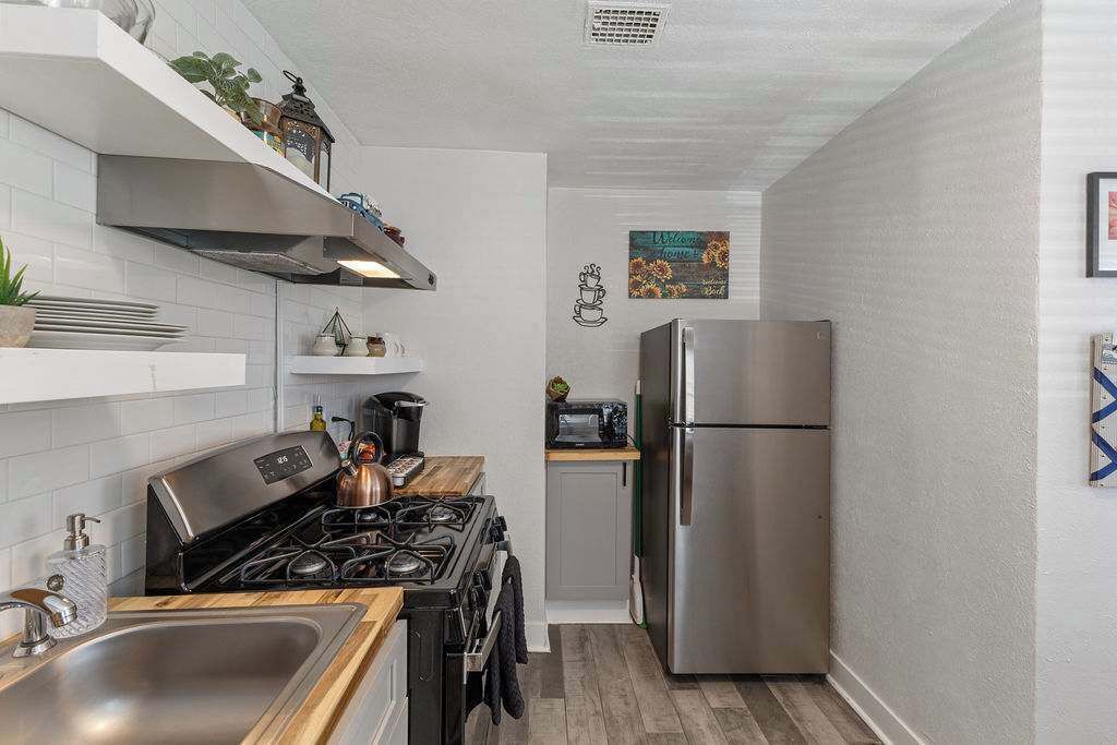 A compact kitchen with a stove, sink, and stainless steel refrigerator.