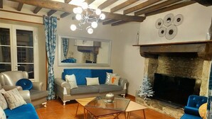 A living room with a fireplace, a sofa, a coffee table, and a television. - Gîte Eloquent (Gratot)