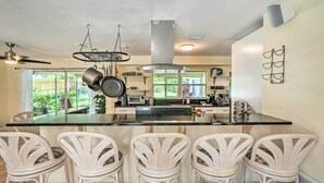 A kitchen with a central island, white wicker chairs, and a ceiling fan. - Book a Paradise for your Family's Florida Vacation!  (Clearwater)