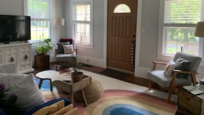 A living room with a television, seating area, and a wooden door. - The Thistle House off Chardon Square (Chardon)