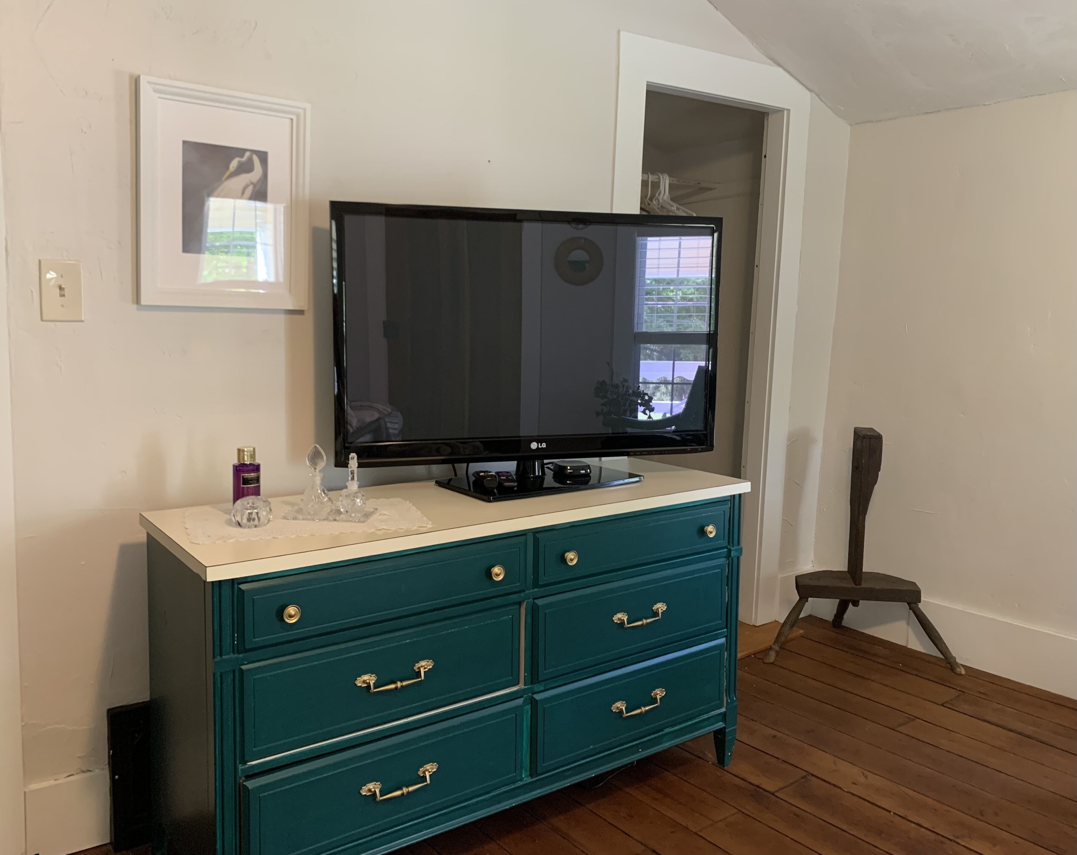 Une commode turquoise avec des tiroirs, et un téléviseur à écran plat fixé au-dessus.