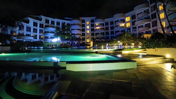 A hotel with multiple balconies, a swimming pool, and a well-lit outdoor area at night. - Kilua Residences by Cityblue (Mombasa)