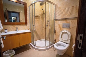 A modern bathroom with a glass-enclosed shower, a sink, and a toilet. - Kilua Residences by Cityblue (Mombasa)