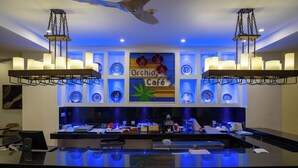 A bar area with a sign reading 'Orchid Café,' a ceiling fan, and a modern light fixture. - Kilua Residences by Cityblue (Mombasa)