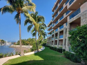 A hotel with a pool, palm trees, and a marina in the background.