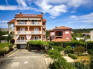 A multi-story building with balconies, a garden area, and a view of the surrounding landscape. - Studio apartment in Lopar with Air condition, WIFI (4886-5) (Lopar)