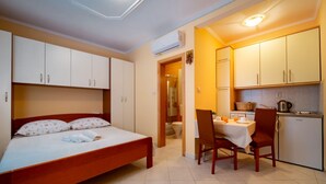Een kleine hotelkamer met een enkel bed, een eettafeltje en een kitchenette.