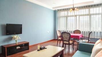 Sala de estar com televisão de tela plana, mesa de centro, sofá e área de jantar com mesa e cadeiras.