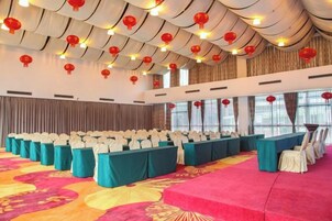 A conference room with rows of tables, chairs, and a red carpet.
