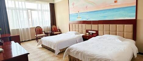A hotel room with two beds, a desk, a chair, and a painting of a seascape.