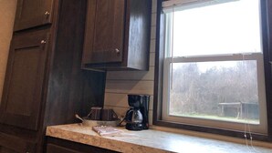 A kitchen with dark wooden cabinets, a window with a view of a garden, and a coffee maker on the counter. - Relax, Enjoy, Explore, On Cane! (Natchez)