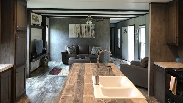 A modern kitchen with a central island, a built-in sink, and dark wood cabinetry. - Relax, Enjoy, Explore, On Cane! (Natchez)
